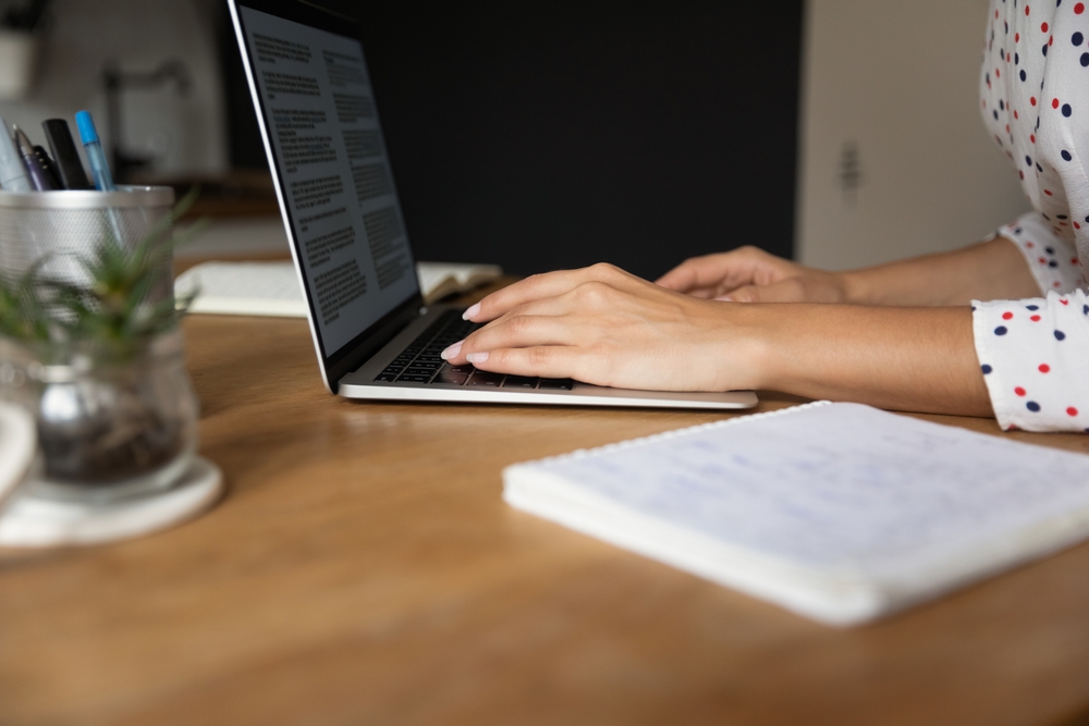 Young-woman-writing-an-article-from-home-on-laptop