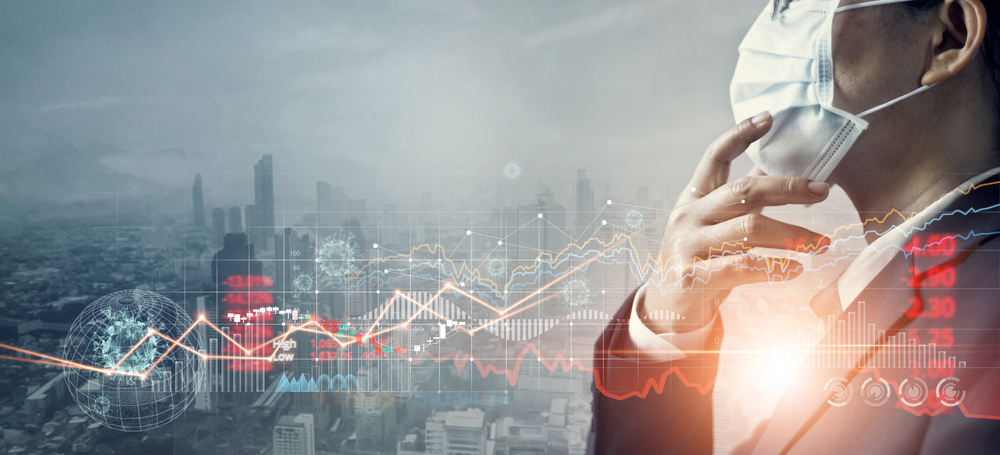 Businessman-wearing-mask-with-hand-on-chin-studying-market-analysis-graph