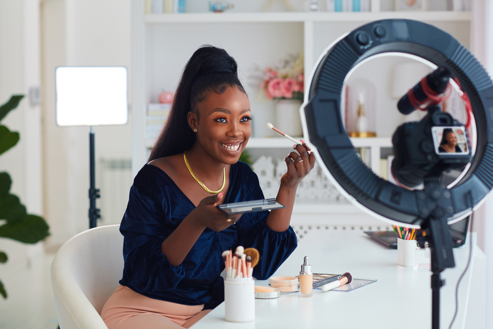 Smiling-young-African-American-woman-applying-makeup-in-front-of-a-camera