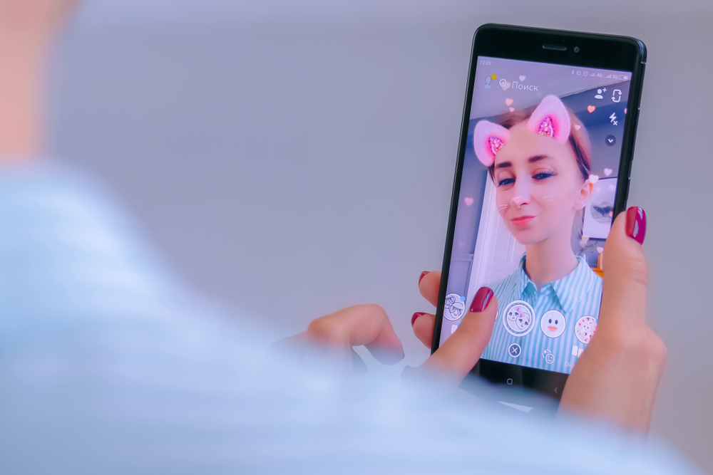 Teen-girl-taking-photo-of-herself-with-pink-cat-filter.