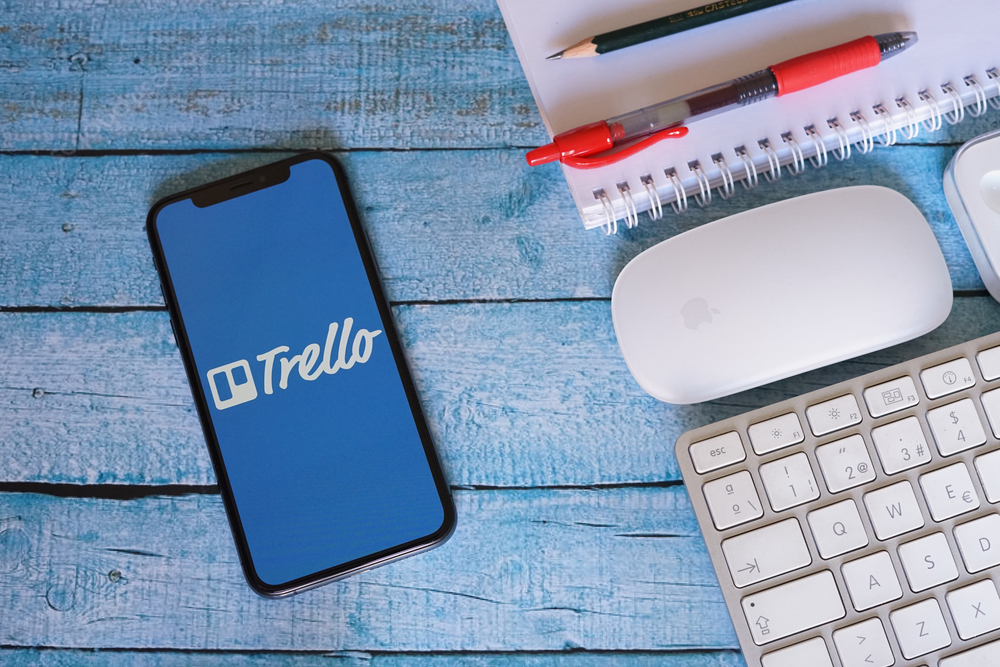 Smartphone-sitting-on-a-blue-table-with-the-Trello-logo-on-the-screen