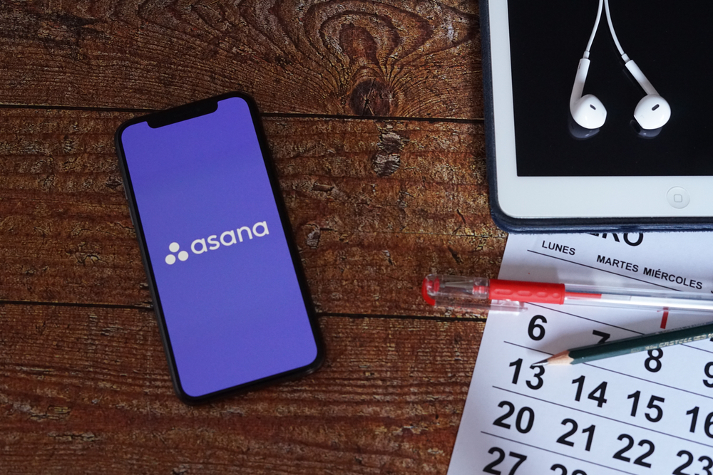 Asana-logo-on-a-smartphone-screen-sitting-on-a-desk-with-a-calendar